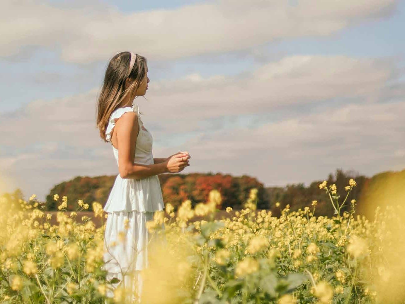 Woman walking through a sunlit canola field in the countryside near Upper Markham